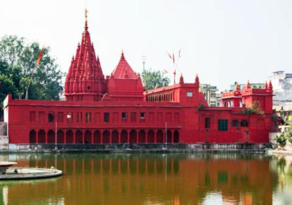 The red facade of Durga Mandir beside its stepped tank.