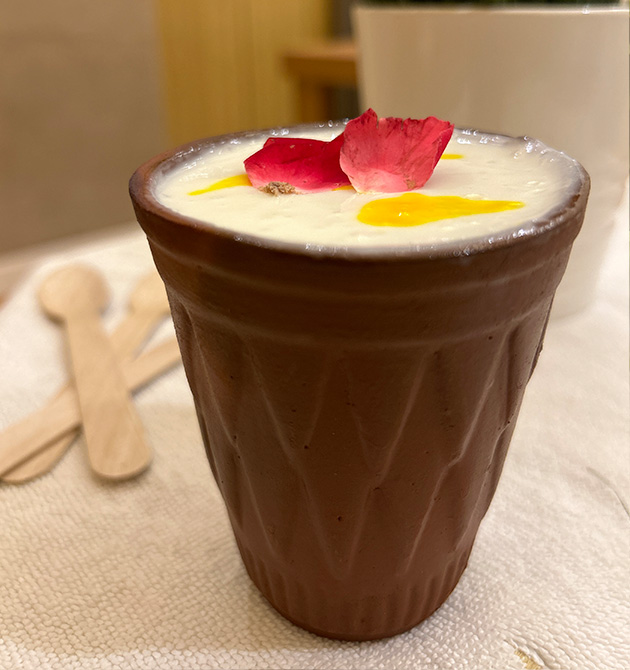 A lassi in a terracotta kulhar topped with saffron and rose petals.