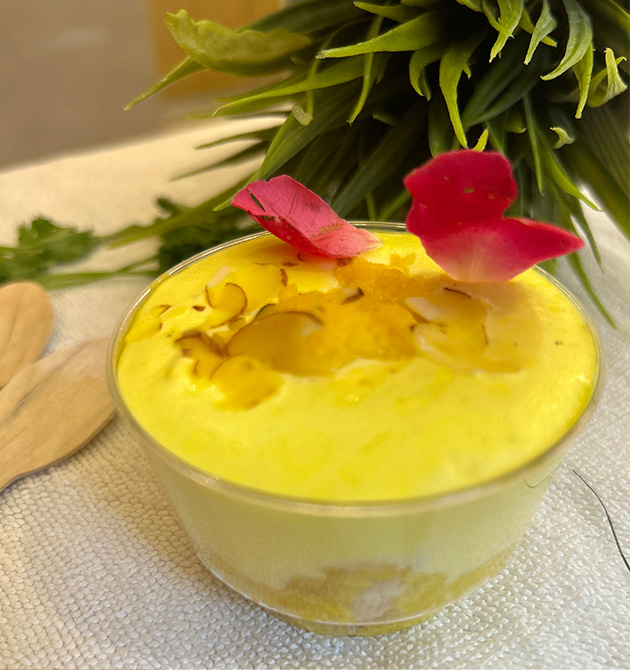 A chilled saffron dessert in a glass bowl, garnished with rose petals.