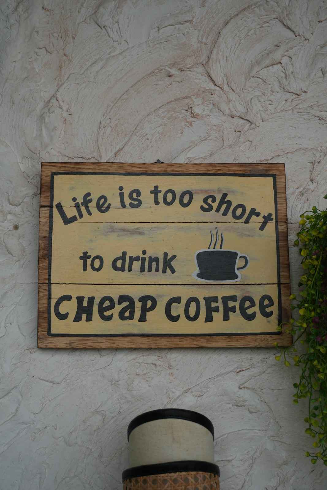 A framed wooden sign reading Life is too short to drink cheap coffee.