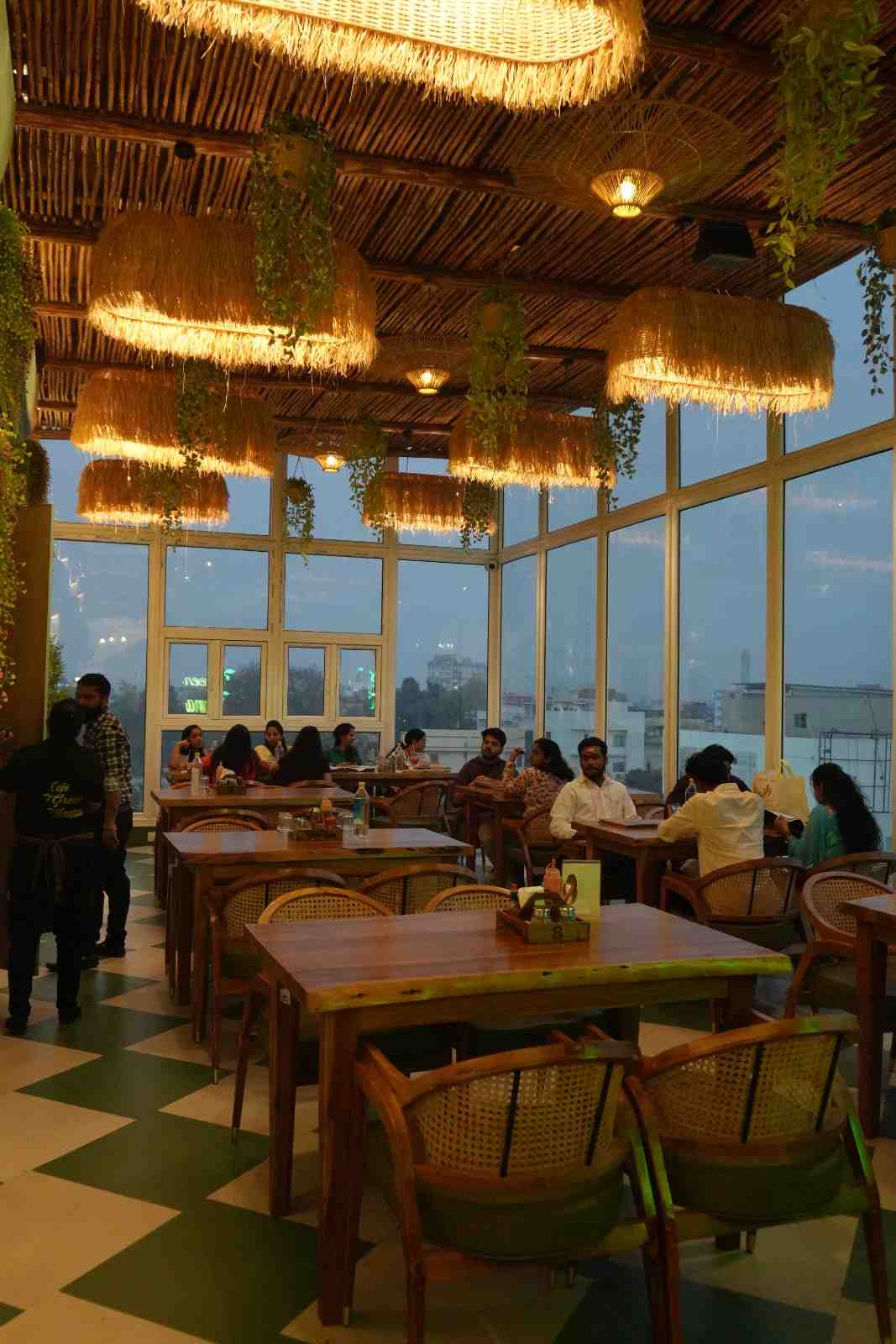 The Cafe Green Mama dining room in daylight, with cane pendant lamps and a checkerboard floor.