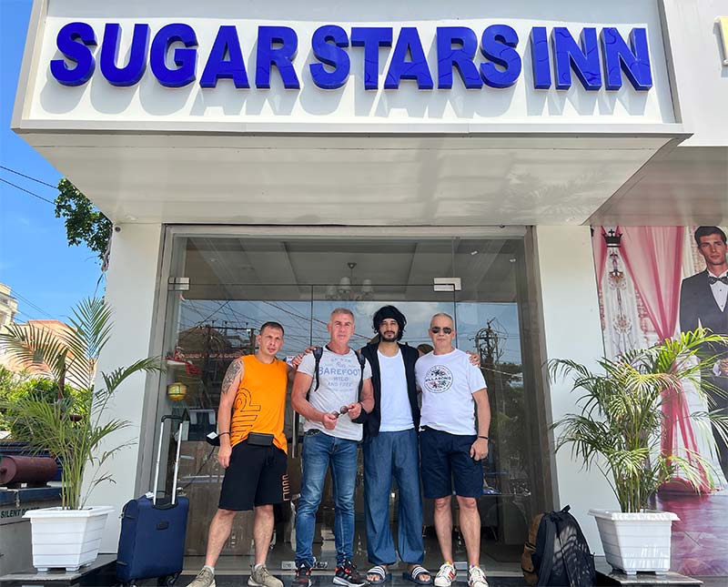 Guests with luggage at the hotel entrance, under the signage.