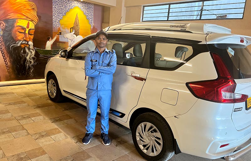 A driver standing beside the hotel car, available for guest hire.