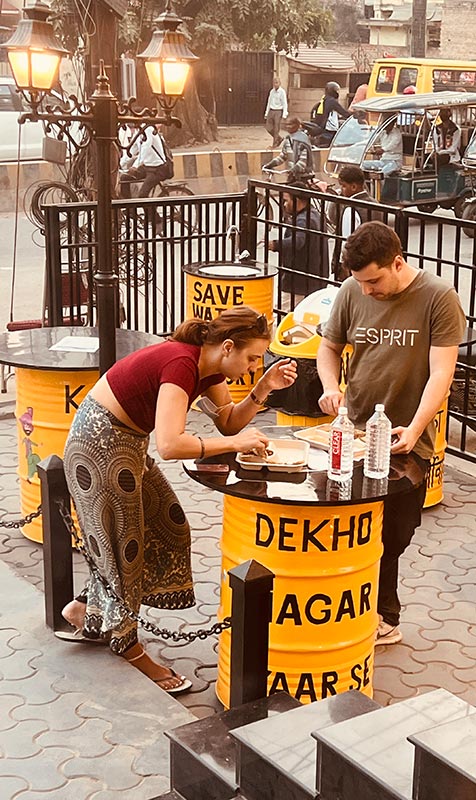 Guests seated at a yellow drum table outside the restaurant.