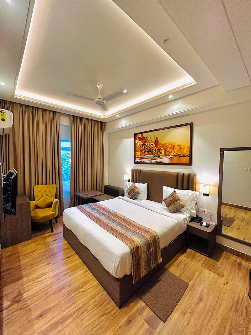 A guest room with a mustard armchair beside the bed and a framed painting of the riverfront.