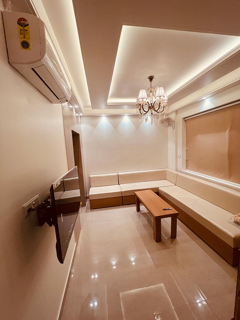 A tiled lounge area with a chandelier and a low wooden bench.