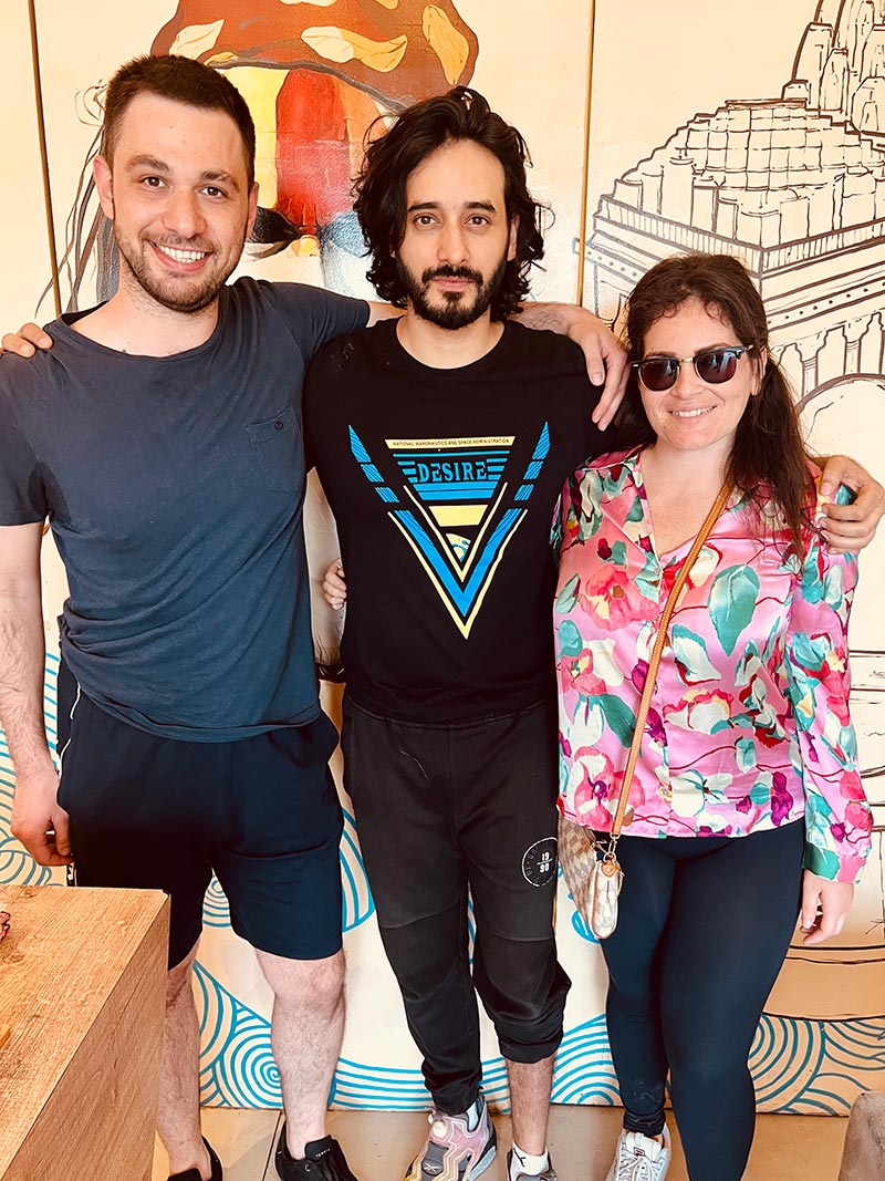 Three guests photographed in front of a painted wall inside the hotel.