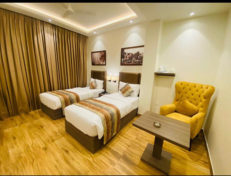 A twin room with two beds, a mustard armchair and framed pictures on the wall.