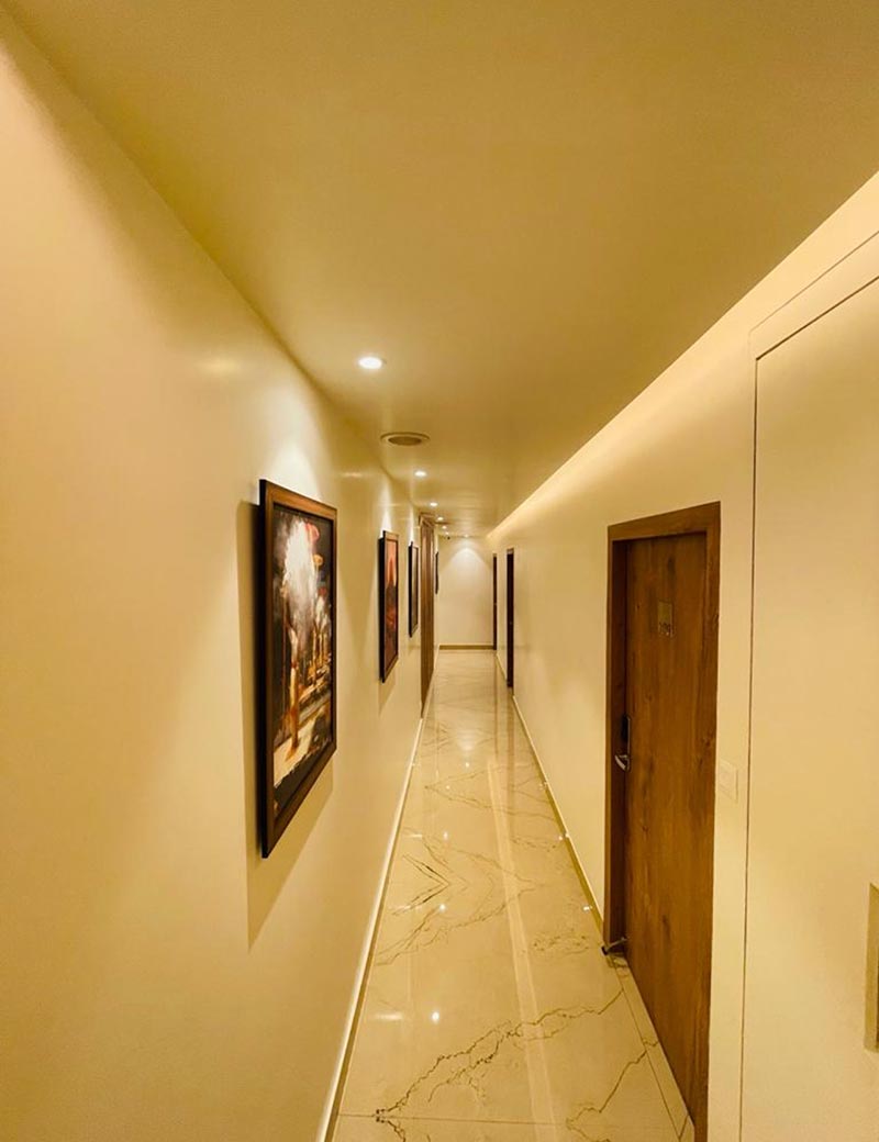 A warmly lit guest corridor lined with room doors.