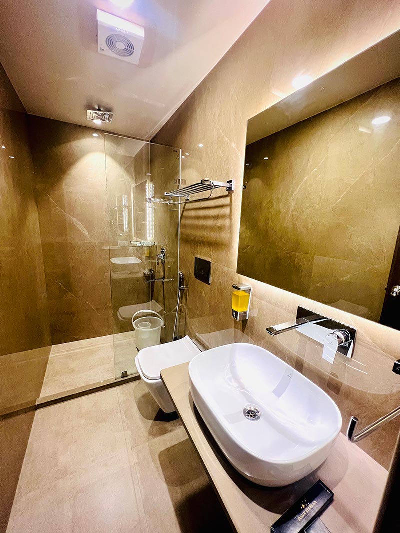 An ensuite bathroom with a vessel basin, mirror and tiled walls.