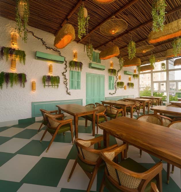 The Green Mama cafe with cane pendant lamps, hanging plants and a checkerboard floor.