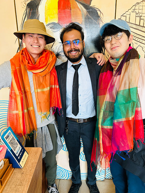 Guests wearing bright printed scarves with a member of the hotel team.
