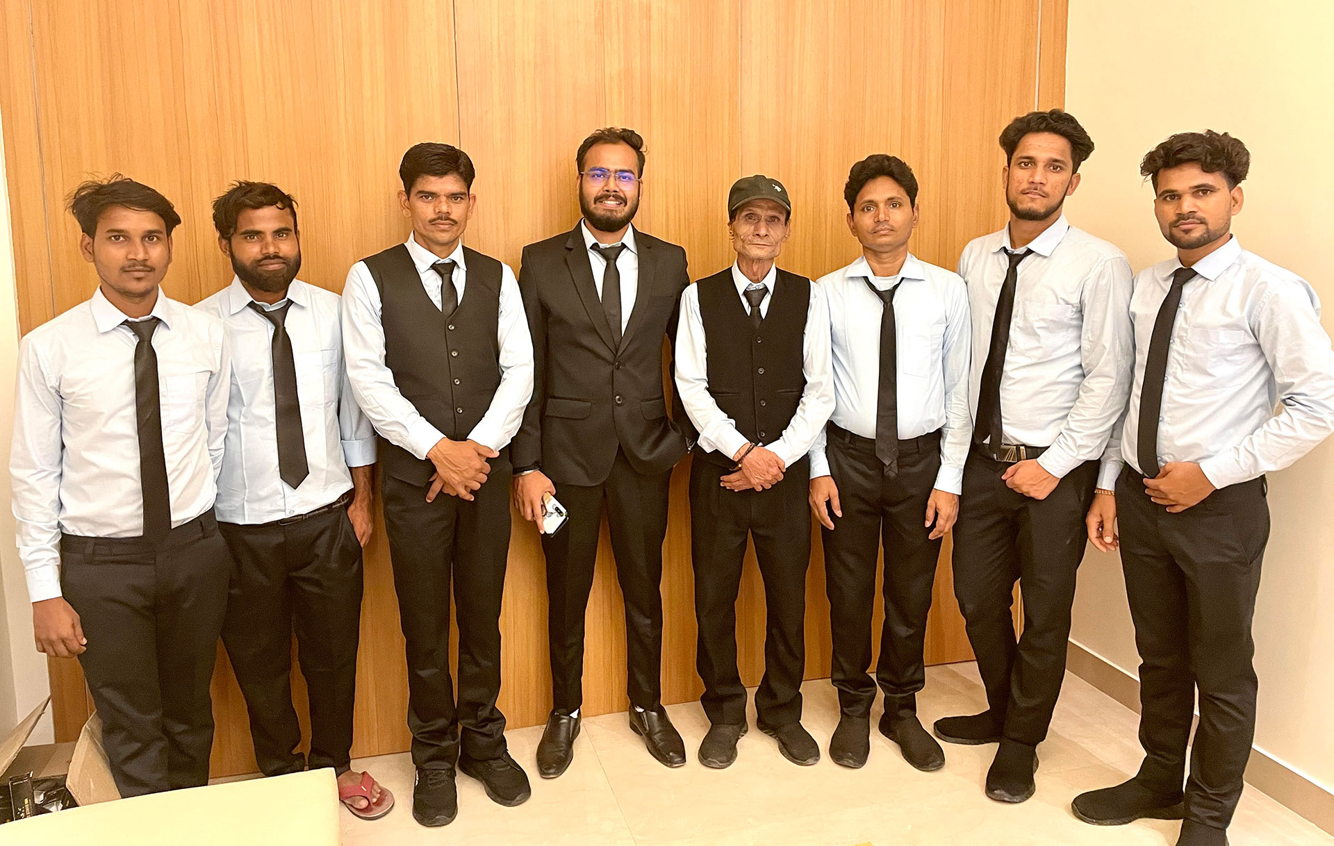 The team of Hotel Sugar Stars Inn, eight staff in white shirts and black ties, standing together indoors.