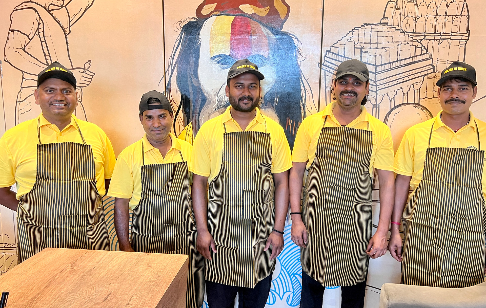 The Punjab Di Truck kitchen team in yellow shirts and aprons.