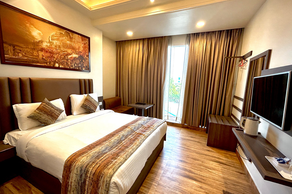 The deluxe room with a king bed and a wide painting of the ghats above the headboard.