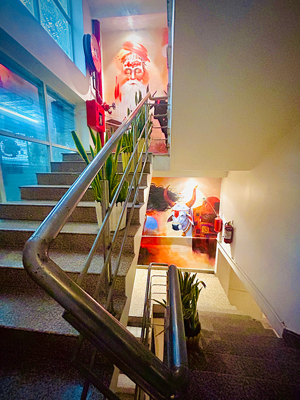 A stairwell hung with large commissioned paintings of a sadhu and of a black bull.