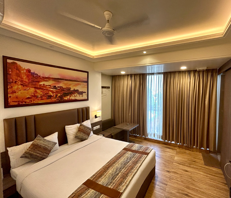 The queen room with a made bed and bedside lamps.